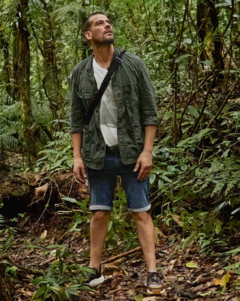 Ein Mann mit Tasche und Shorts im Dschungel